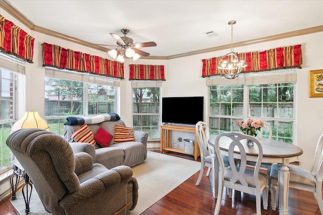 living room with ceiling fan with notable chandelier, wood finished floors, ornamental molding, and a healthy amount of sunlight