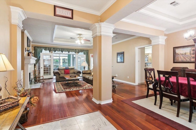 living room with visible vents, ornate columns, a ceiling fan, a raised ceiling, and wood-type flooring