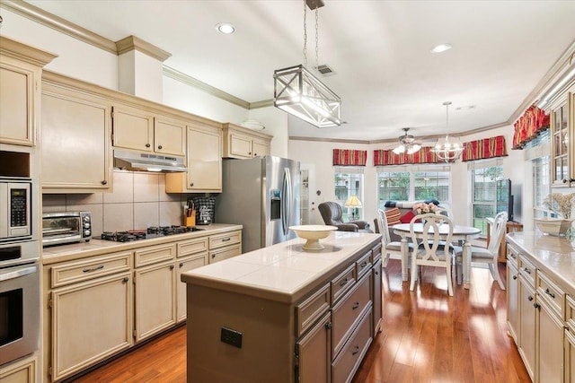 kitchen featuring cream cabinets, stainless steel appliances, and under cabinet range hood