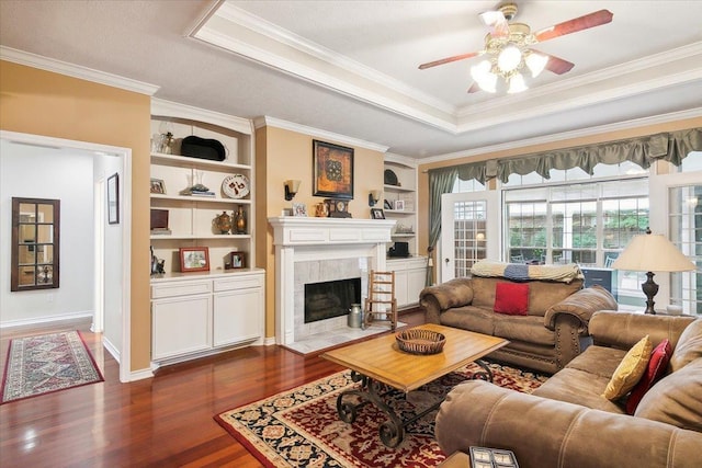 living area featuring a ceiling fan, dark wood-style flooring, a tray ceiling, and crown molding