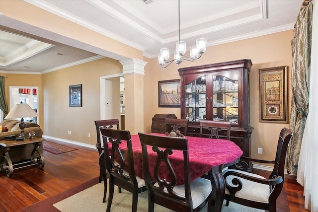 dining area featuring a tray ceiling, wood finished floors, crown molding, and baseboards