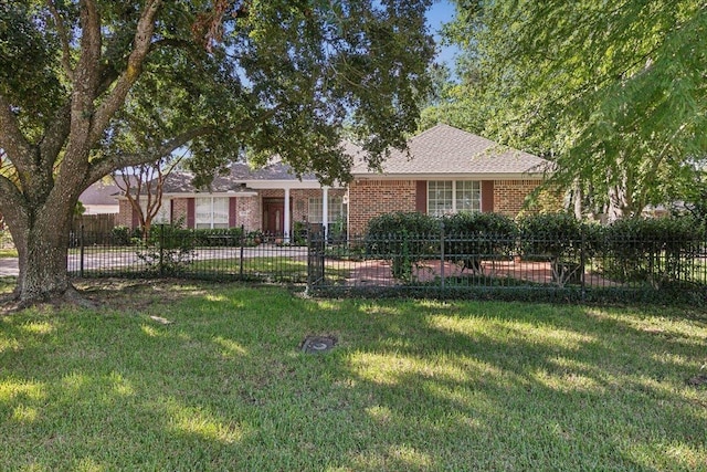 ranch-style home featuring a front lawn, brick siding, a shingled roof, and fence private yard