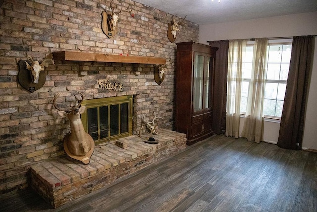 interior space featuring a healthy amount of sunlight, a fireplace, brick wall, and dark wood-type flooring