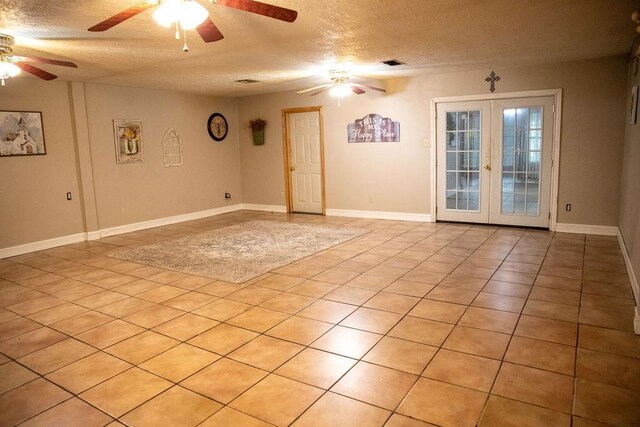 tiled empty room with french doors and a textured ceiling