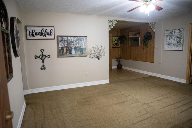 empty room with carpet flooring, ceiling fan, and a textured ceiling