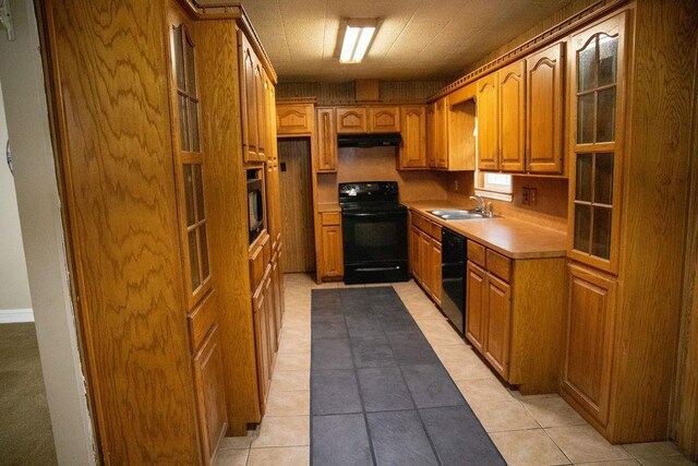 kitchen with black appliances, light tile patterned floors, and sink