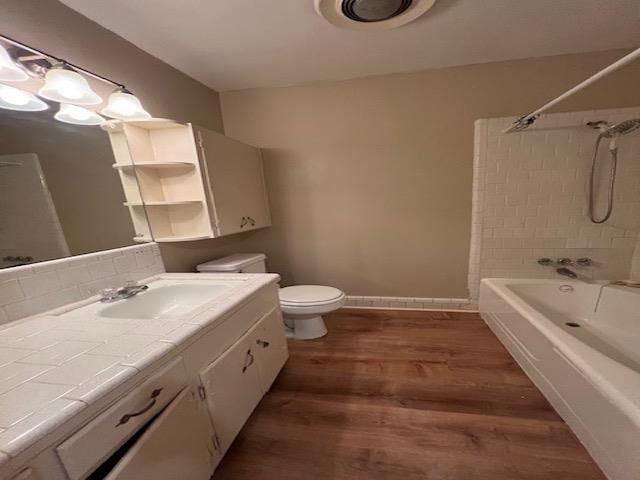 full bathroom with tiled shower / bath combo, wood-type flooring, vanity, and toilet