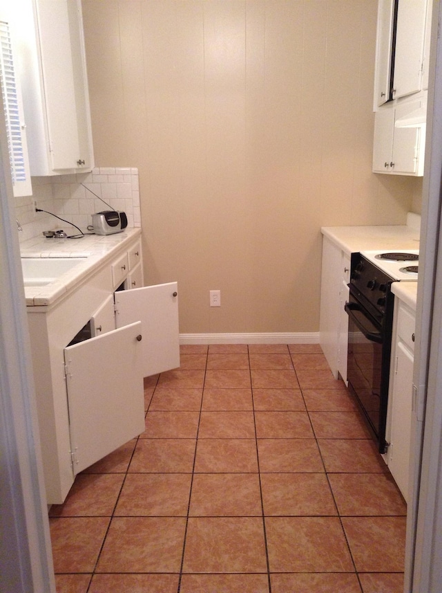 kitchen featuring light tile patterned flooring, black electric range, white cabinets, and backsplash