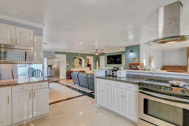 kitchen featuring stainless steel appliances, ceiling fan, wall chimney range hood, light tile patterned floors, and white cabinets