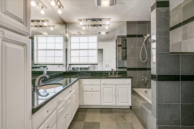 bathroom with a textured ceiling, vanity, and independent shower and bath