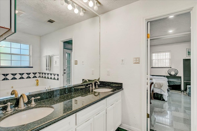 bathroom featuring a bathing tub, vanity, and a textured ceiling