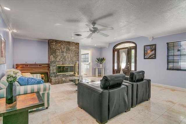 living room with a tiled fireplace, crown molding, ceiling fan, and a textured ceiling