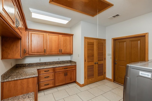 114 Holmes Rd, Lumberton, TX 77657 - kitchen with brown cabinets, washer / dryer, light tile patterned flooring, and baseboards