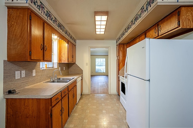 kitchen with decorative backsplash, white appliances, crown molding, and sink