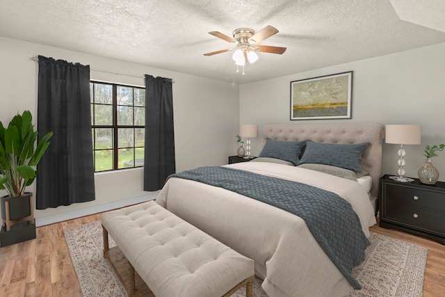 bedroom with ceiling fan, light wood-type flooring, and a textured ceiling