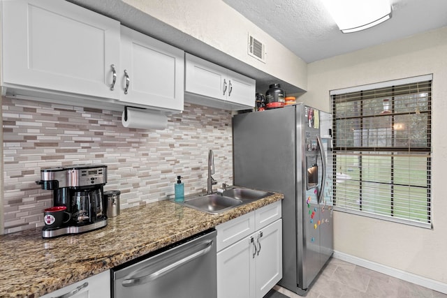 kitchen featuring backsplash, white cabinets, appliances with stainless steel finishes, and a sink