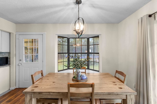 dining room with dark wood-type flooring, a chandelier, and a textured ceiling