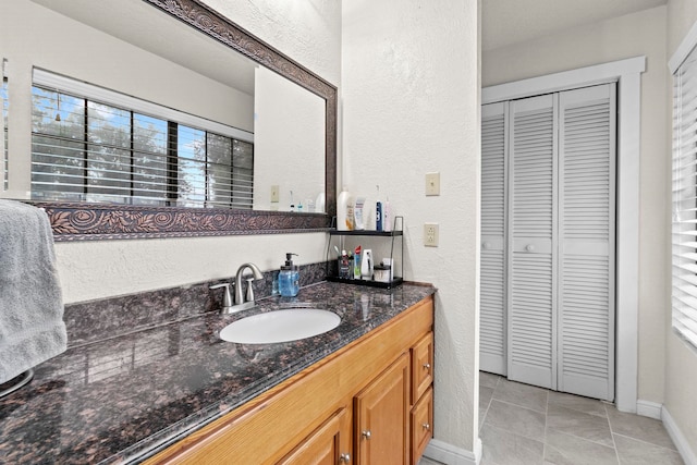 bathroom with a closet, vanity, and a textured wall