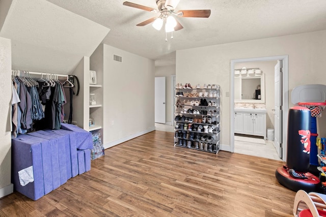 interior space featuring baseboards, visible vents, light wood-style flooring, ensuite bathroom, and a textured ceiling