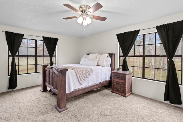 carpeted bedroom with multiple windows, a textured ceiling, and a ceiling fan