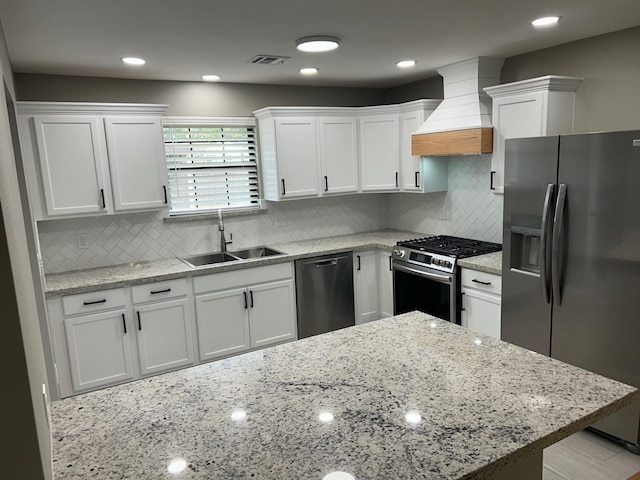 kitchen featuring decorative backsplash, custom exhaust hood, stainless steel appliances, sink, and white cabinetry