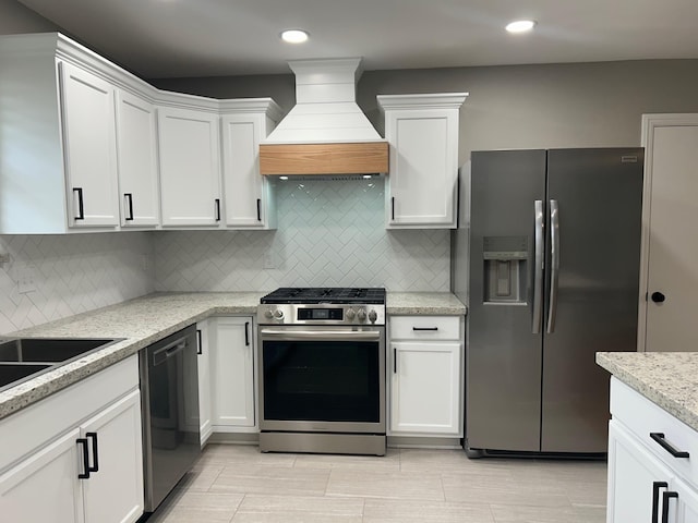 kitchen with backsplash, white cabinets, stainless steel appliances, and custom range hood