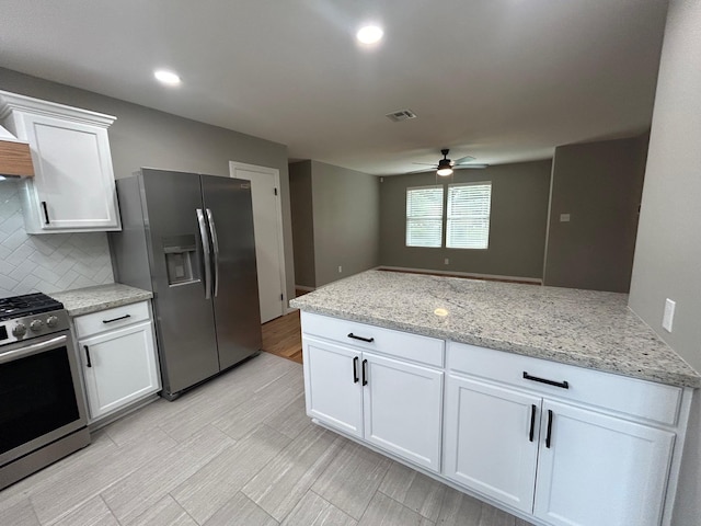 kitchen featuring ceiling fan, light stone countertops, tasteful backsplash, white cabinetry, and stainless steel appliances