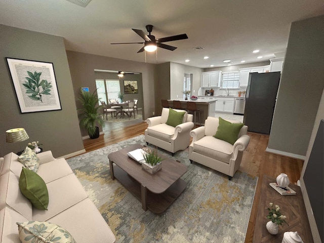 living room with a healthy amount of sunlight, sink, ceiling fan, and hardwood / wood-style floors