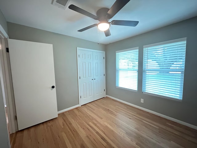 unfurnished bedroom with light wood-type flooring, a closet, and ceiling fan