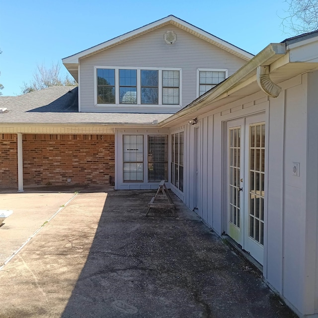 rear view of property with french doors, a patio, brick siding, and board and batten siding