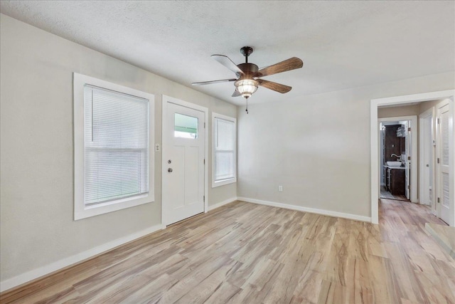 entrance foyer with light wood-type flooring, baseboards, and a ceiling fan