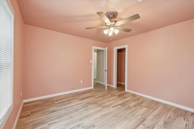 unfurnished bedroom featuring light wood-type flooring, baseboards, and a ceiling fan