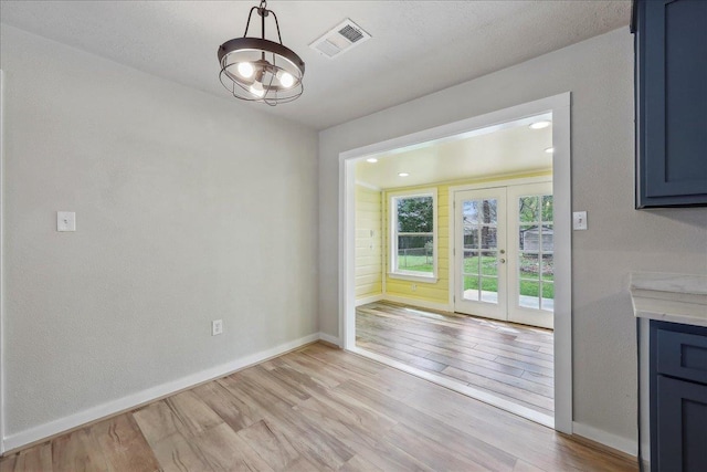 unfurnished dining area with french doors, light wood-type flooring, and baseboards