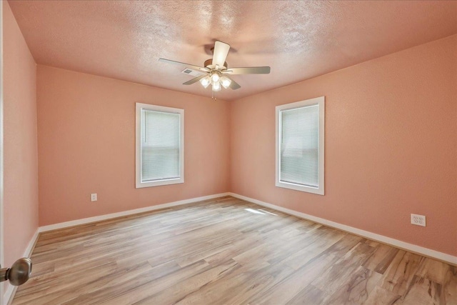 spare room featuring light wood-style floors, ceiling fan, baseboards, and a textured ceiling