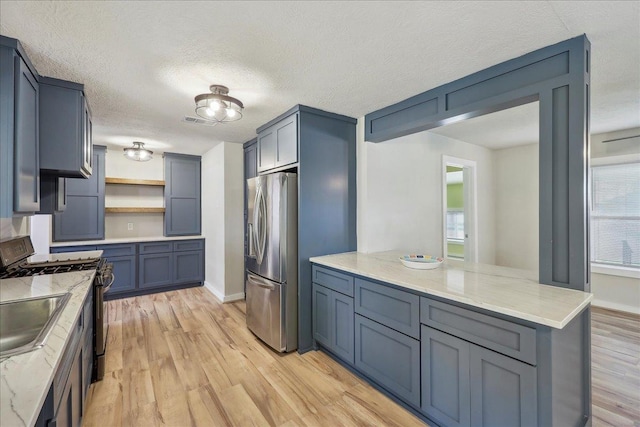 kitchen featuring stainless steel fridge with ice dispenser, gas stove, open shelves, light wood-style floors, and light stone counters