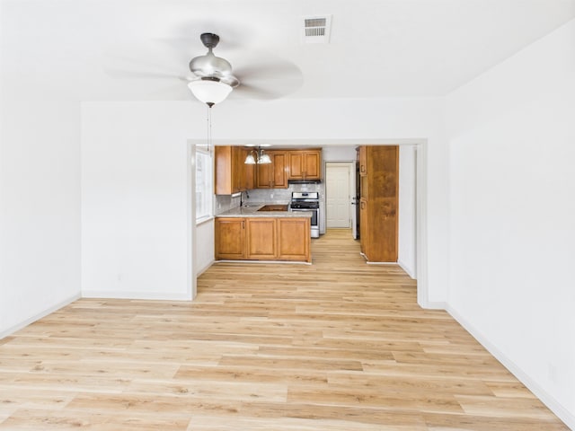 1832 19th St, Port Arthur, TX 77640 - kitchen with stainless steel gas range, brown cabinetry, light wood-style floors, and a ceiling fan