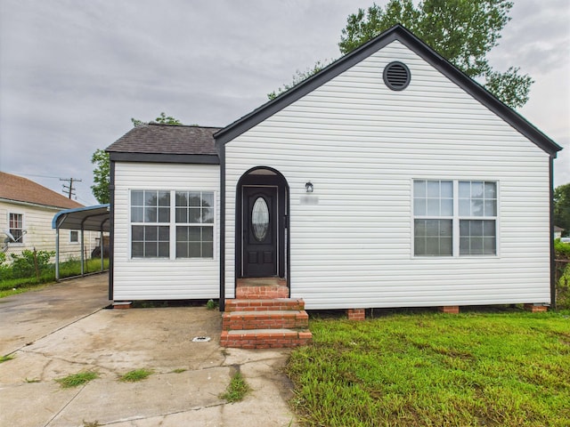 1832 19th St, Port Arthur, TX 77640 - view of front facade with concrete driveway, entry steps, a front yard, a detached carport, and a shingled roof