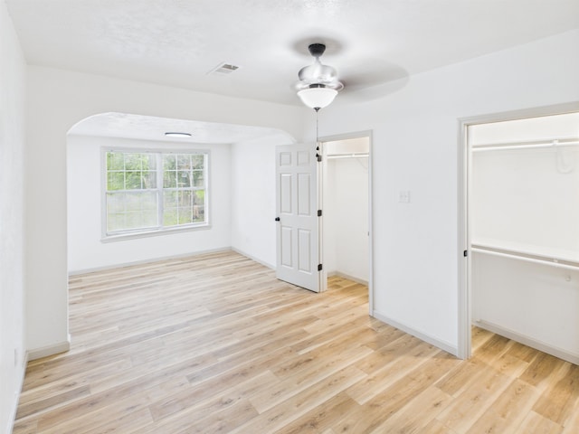 1832 19th St, Port Arthur, TX 77640 - unfurnished bedroom featuring wood finished floors, a walk in closet, arched walkways, and a ceiling fan