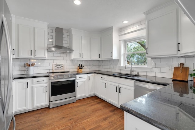 kitchen featuring wall chimney exhaust hood, stainless steel appliances, sink, and white cabinets