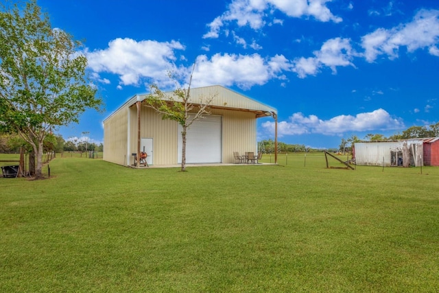 back of property featuring a garage, a lawn, and an outdoor structure