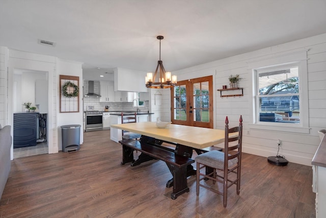 dining area with dark hardwood / wood-style flooring, sink, french doors, and an inviting chandelier