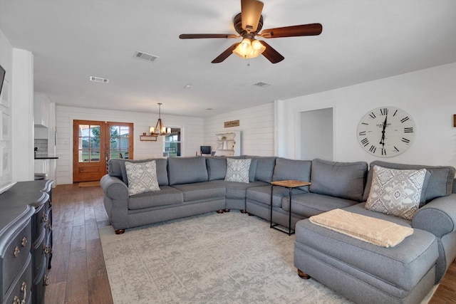 living room featuring hardwood / wood-style flooring, ceiling fan with notable chandelier, and french doors