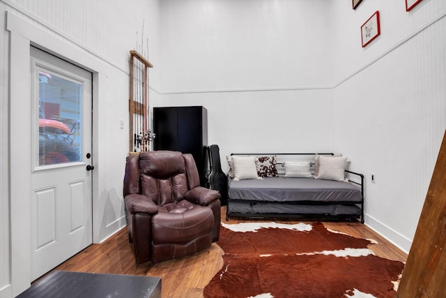 sitting room featuring a towering ceiling and hardwood / wood-style floors