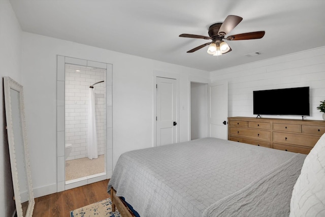 bedroom with dark wood-type flooring, ceiling fan, and ensuite bath