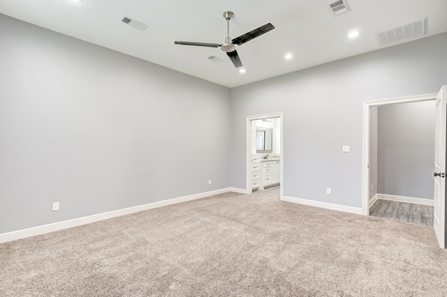 unfurnished bedroom featuring ceiling fan, light colored carpet, and ensuite bath