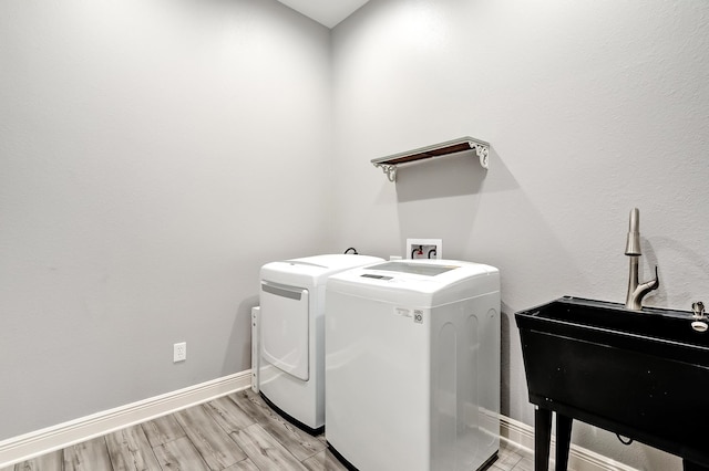 laundry room with independent washer and dryer, light wood-type flooring, and sink