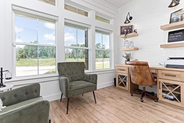 office with light wood-type flooring and brick wall