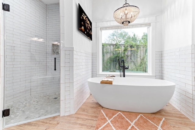 bathroom featuring hardwood / wood-style floors, an inviting chandelier, sink, tile walls, and independent shower and bath