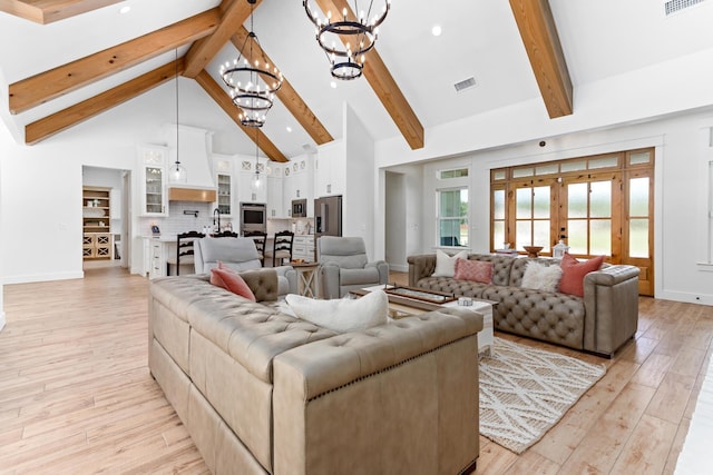 living room with high vaulted ceiling, french doors, an inviting chandelier, beamed ceiling, and light hardwood / wood-style floors