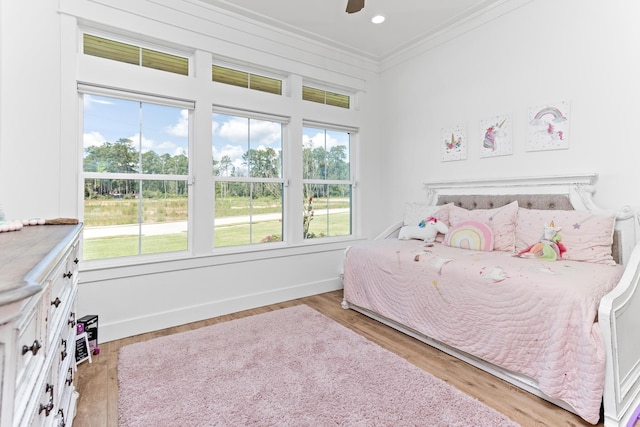 bedroom featuring ceiling fan, light wood-type flooring, crown molding, and multiple windows